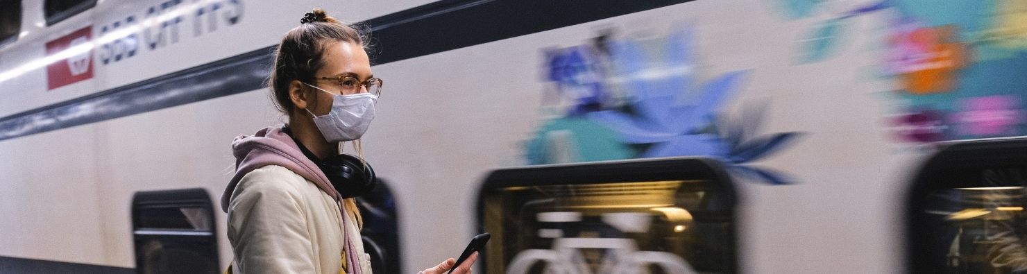 Podróże w pandemię pociągiem kobieta w maseczce przy pociągu
