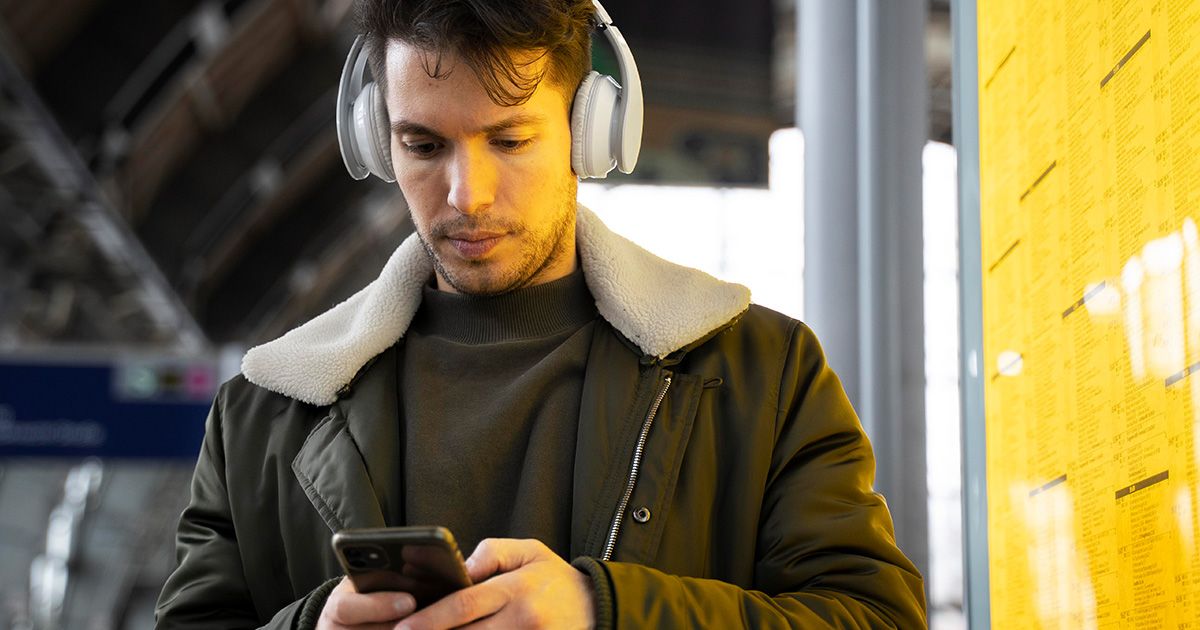 Nowy rozkład jazdy PKP - najważniejsze informacje i zmiany na 2024/25 rok Mężczyzna w słuchawkach z telefonem w ręku